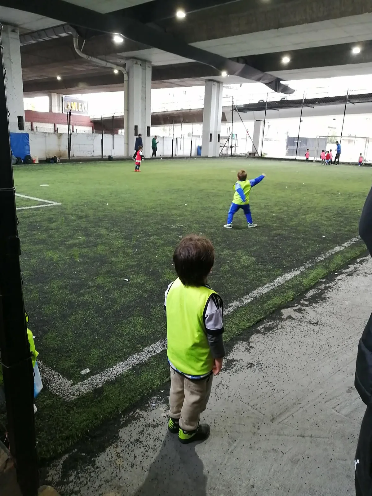 高速道路の高架下にある人工芝コートで練習する幼児たちのサッカー教室