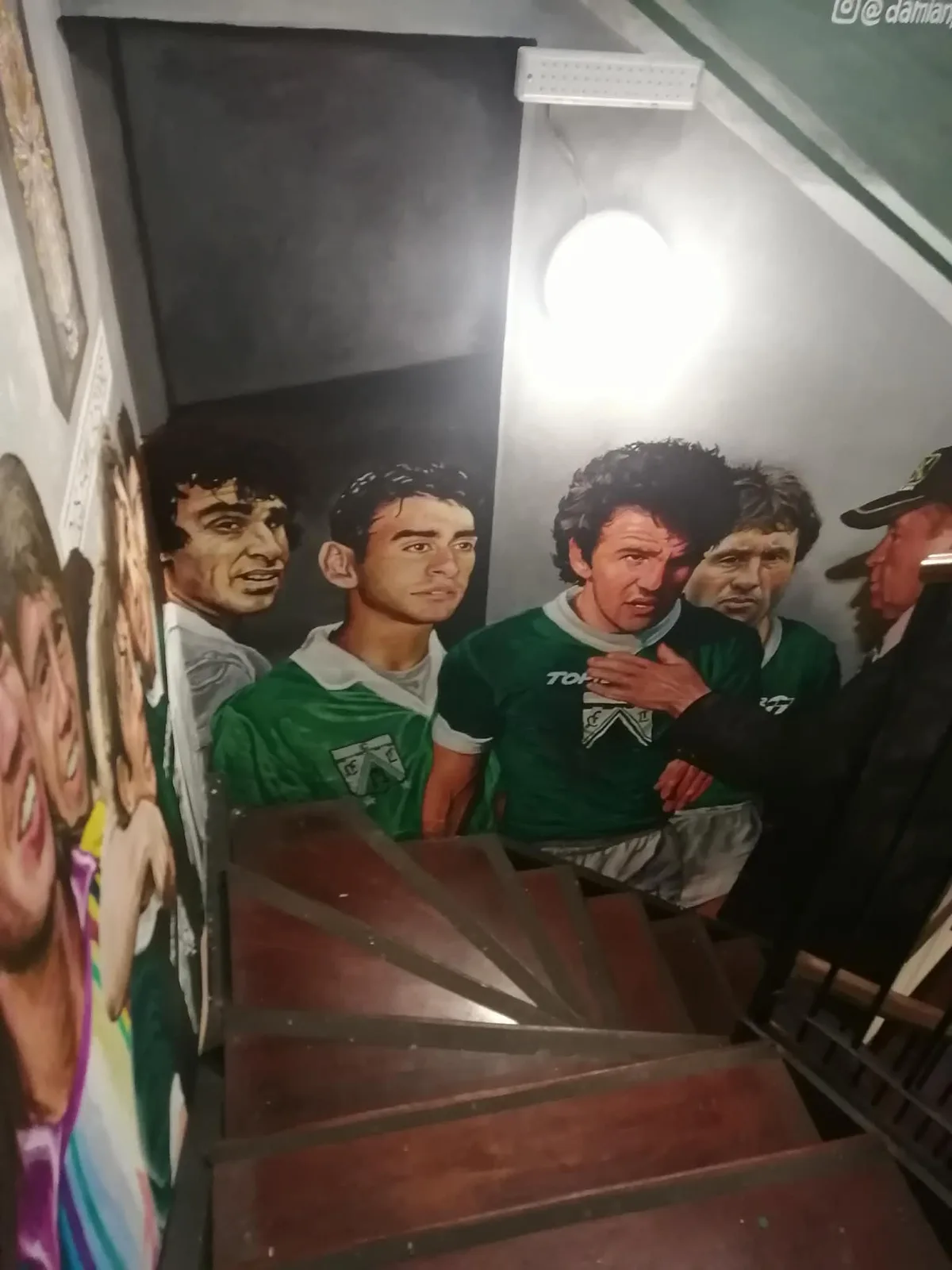 バーの階段の壁一面に描かれた、緑と白のユニフォーム姿の選手たちの壁画