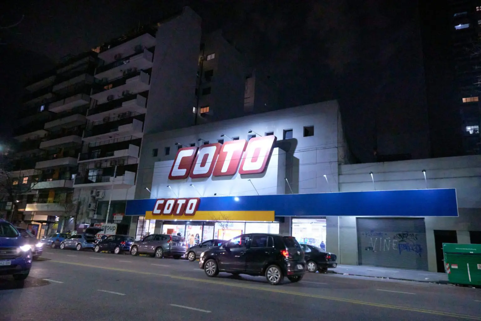 夜の大通りに面したスーパーマーケット。看板が明るく灯っている