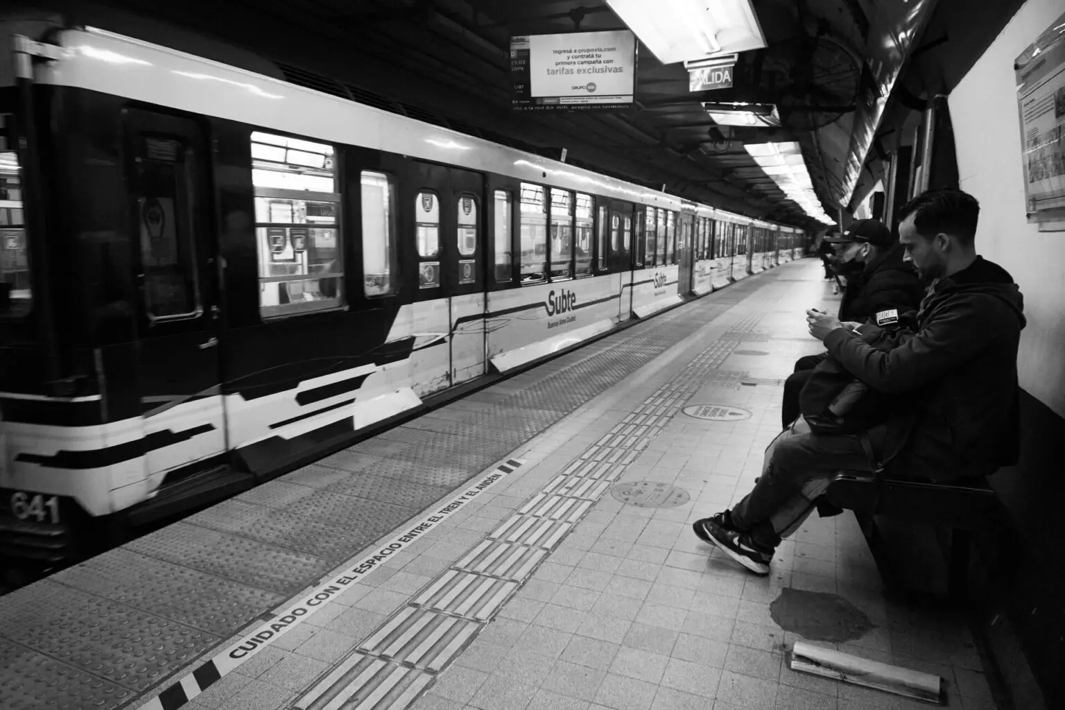ホームに入ってくる車両。側面に Subte のロゴ、頭上に SALIDA の案内表示