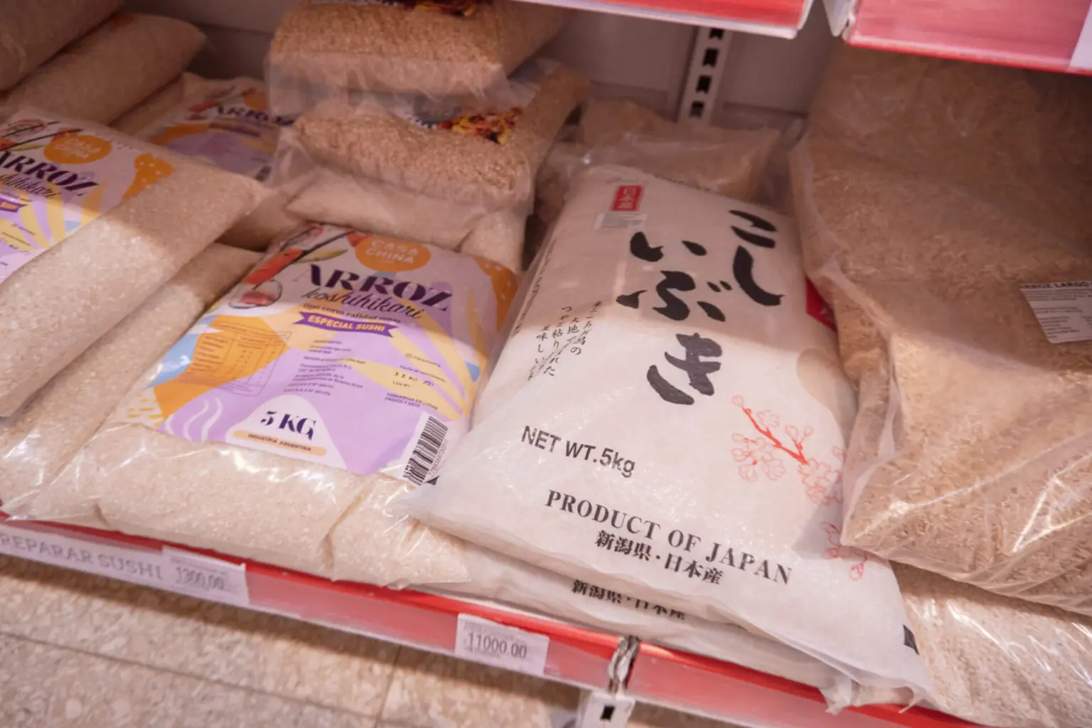 スーパーの棚に並ぶ日本の米。新潟産の袋と、アルゼンチン産コシヒカリの袋に値札が付いている